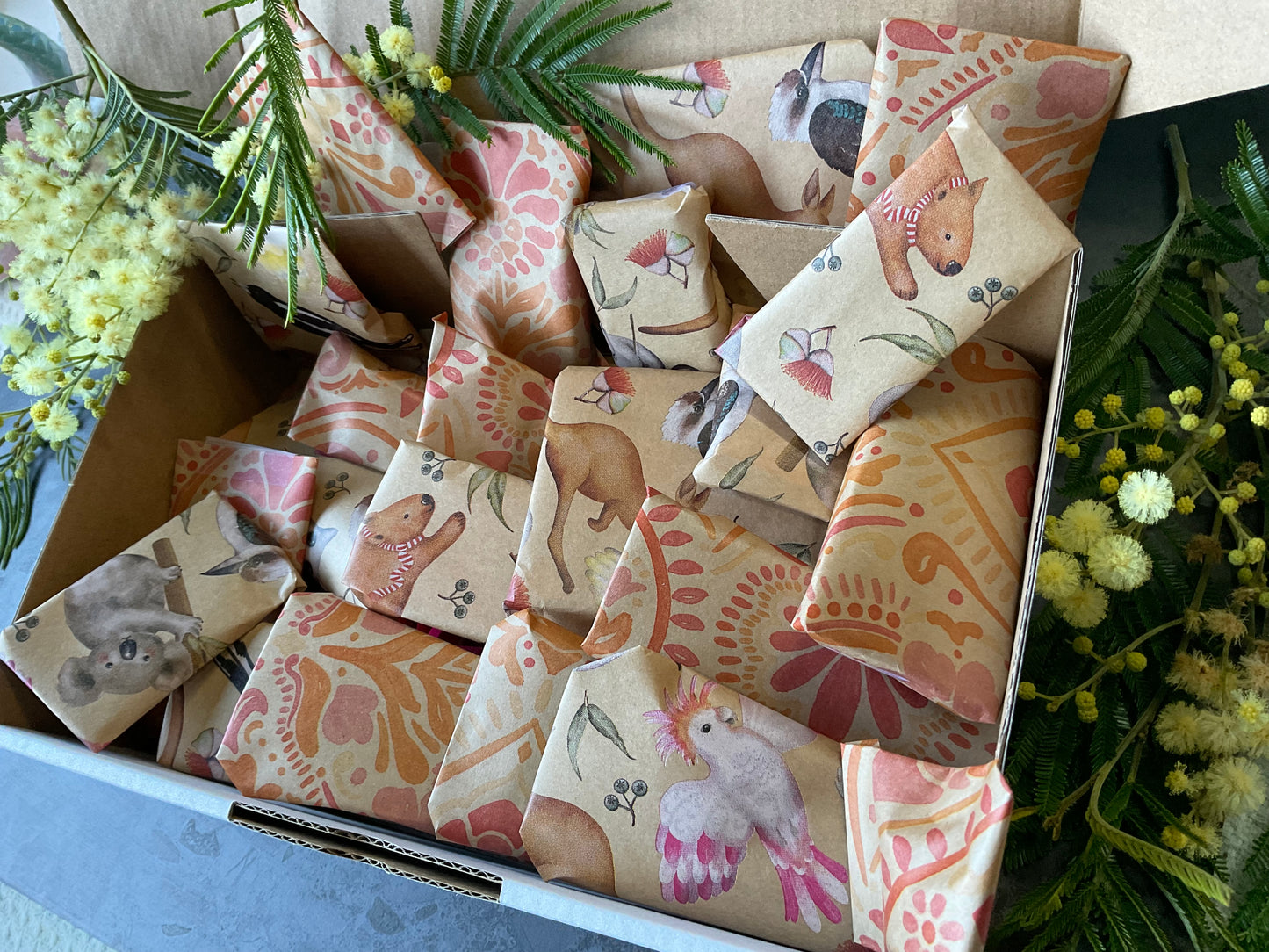 A box of individually wrapped small polymer clay tools as a gift. Each item is wrapped in a lovely kraft and print design including koalas and batik stamped flowers. Gifts include polymer clay cutters, textures, silkscreens and matching cutters and textures.
