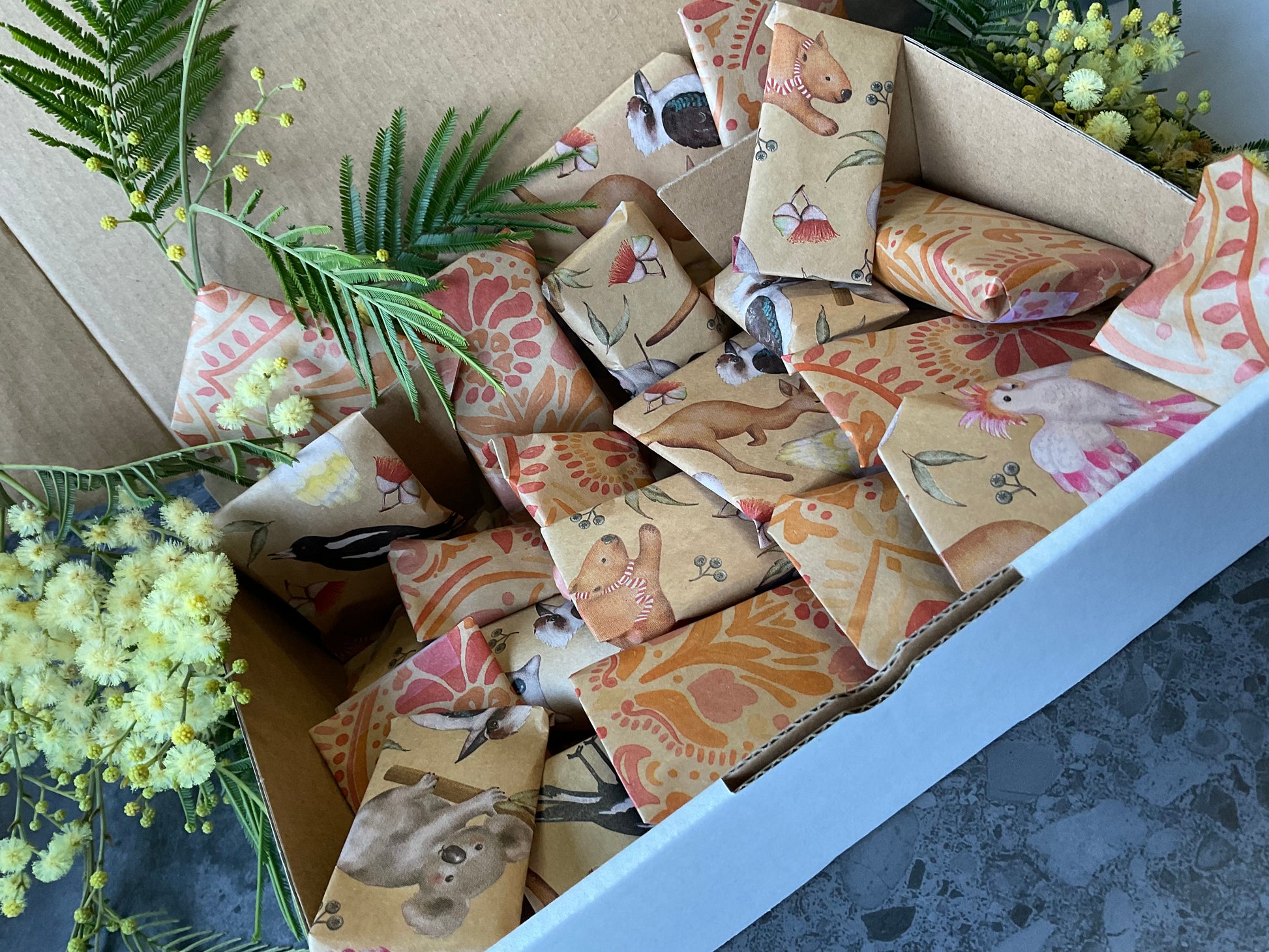 A box of individually wrapped small polymer clay tools as a gift. Each item is wrapped in a lovely kraft and print design including koalas and batik stamped flowers. Gifts include polymer clay cutters, textures, silkscreens and matching cutters and textures.