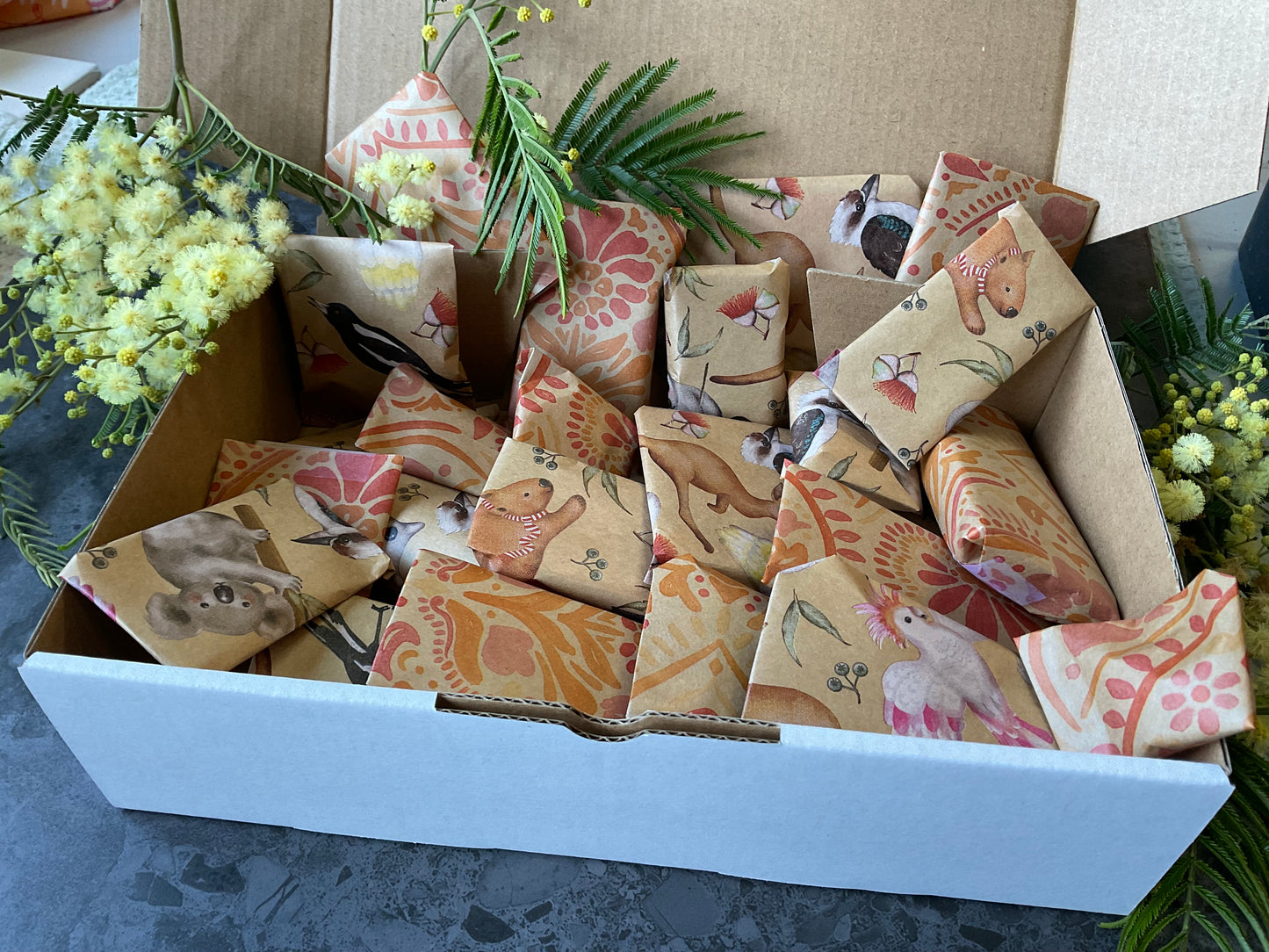 A box of individually wrapped small polymer clay tools as a gift. Each item is wrapped in a lovely kraft and print design including koalas and batik stamped flowers. Gifts include polymer clay cutters, textures, silkscreens and matching cutters and textures.