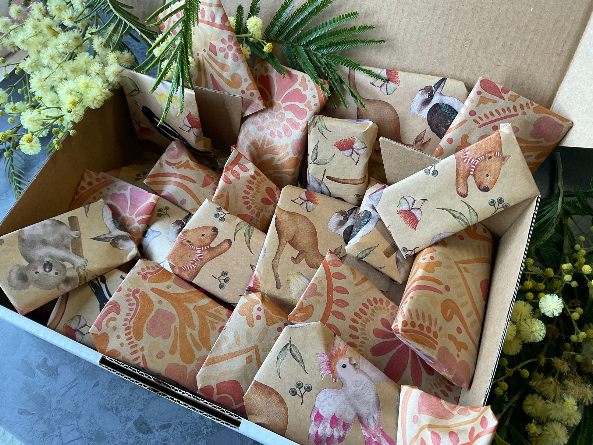 A box of individually wrapped small polymer clay tools as a gift. Each item is wrapped in a lovely kraft and print design including koalas and batik stamped flowers. Gifts include polymer clay cutters, textures, silkscreens and matching cutters and textures.
