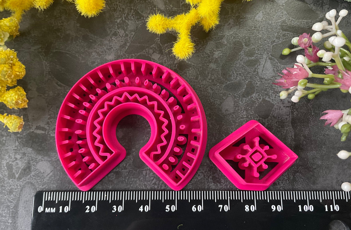 3d printed bright pink polymer clay cutters in different sizes arranged on a dark textured surface, surrounded by decorative yellow and white flowers. Desert Arch Polymer Clay Cutter Set