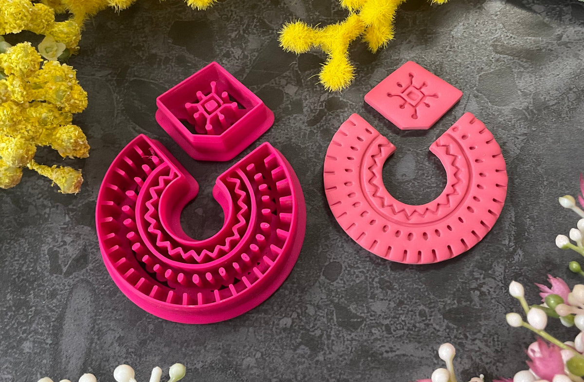 3d printed bright pink polymer clay cutters in different sizes arranged on a dark textured surface, surrounded by decorative yellow and white flowers. Desert Arch Polymer Clay Cutter Set