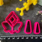 A set of bright pink and turquoise 3d printed polymer clay cutters arranged on a dark textured surface with decorative flowers around the edges. The set includes large fan-shaped stamping cutters, smaller matching cutters, and pointed cone-shaped cutters. First Light Polymer Clay Cutter Set