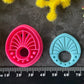 Three 3d printed polymer clay cutters in bright pink, arranged on a dark textured surface surrounded by colorful flowers. Halo Beam Polymer Clay Cutter