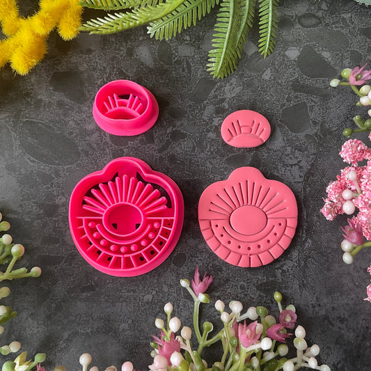Bright pink 3d printed polymer clay cutters arranged on a dark textured surface, surrounded by decorative flowers and greenery. Morning Ray Polymer Clay Cutter Set
