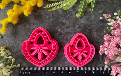 Hot  pink teardrop-shaped polymer clay craft cutters arranged on a dark textured surface with decorative flowers and greenery around them. Nomad Teardrop Polymer Clay Cutter