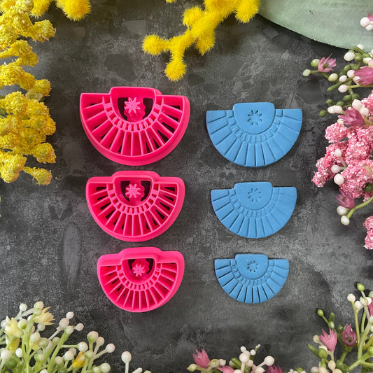 Three pink 3d printed polymer clay cutters arranged on a dark textured surface with decorative yellow and pink flowers around the edges. Palm Fan Polymer Clay Cutter