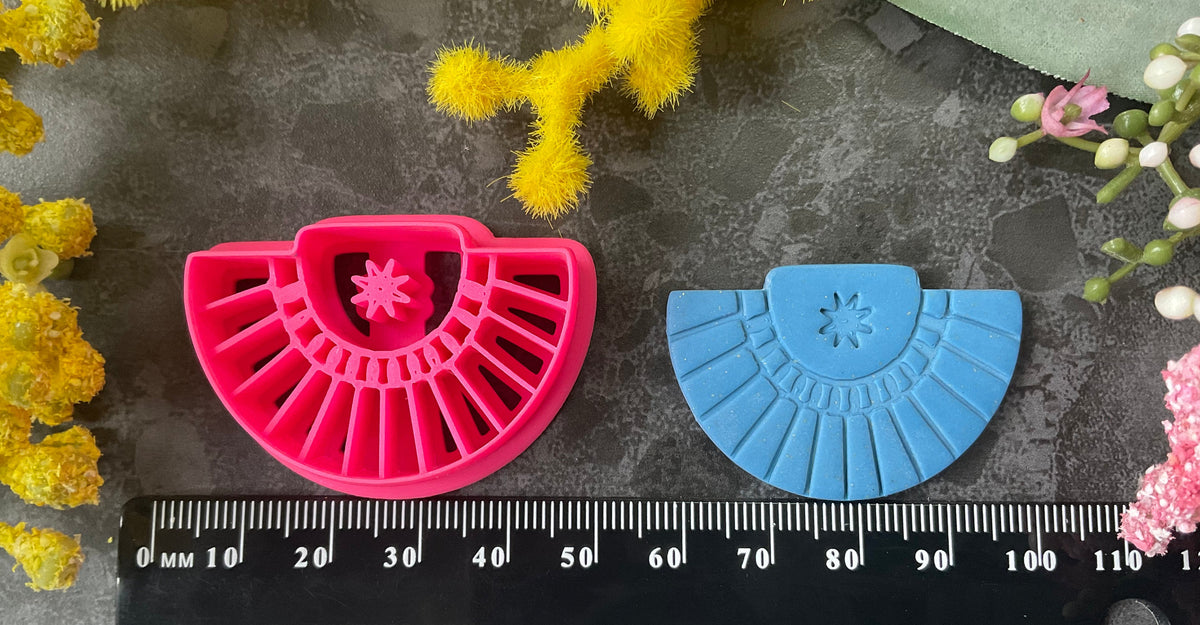 Three pink 3d printed polymer clay cutters arranged on a dark textured surface with decorative yellow and pink flowers around the edges. Palm Fan Polymer Clay Cutter