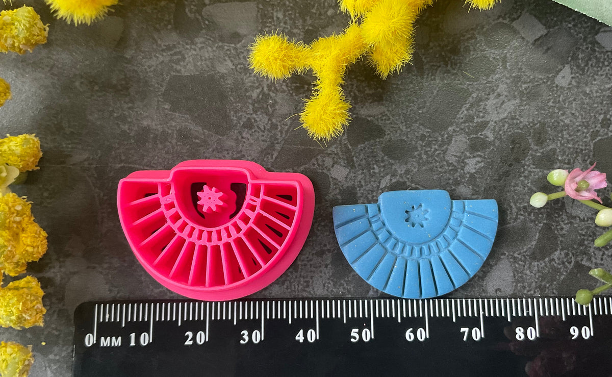 Three pink 3d printed polymer clay cutters arranged on a dark textured surface with decorative yellow and pink flowers around the edges. Palm Fan Polymer Clay Cutter