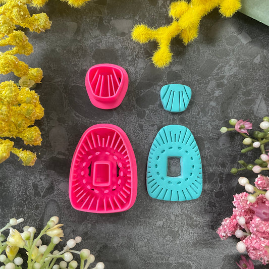 Bright pink 3d printed polymer clay cutters in bright pink and turquoise arranged on a dark textured surface, surrounded by yellow and pink flowers. Solstice Bloom Polymer Clay Cutter Set