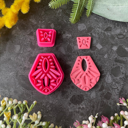 Bright pink3d printed polymer clay cutters in different sizes arranged on a dark textured surface, surrounded by decorative flowers and greenery. Terracotta Tale Polymer Clay Cutter Set